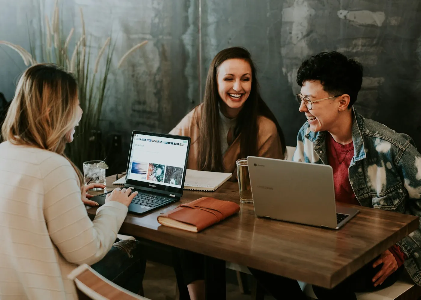 Colleagues talking around a table with laptops