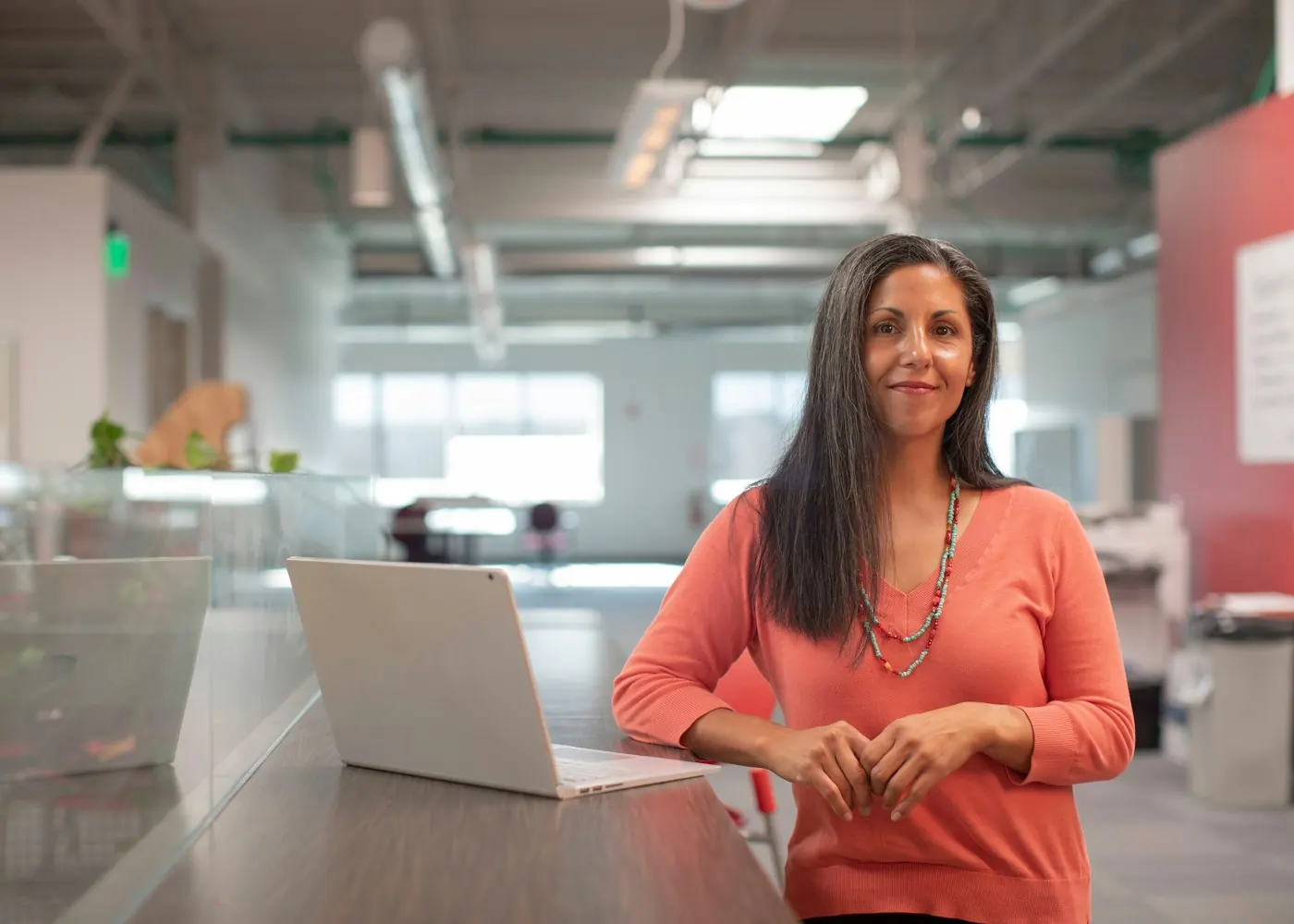 Professional standing in an office with a laptop